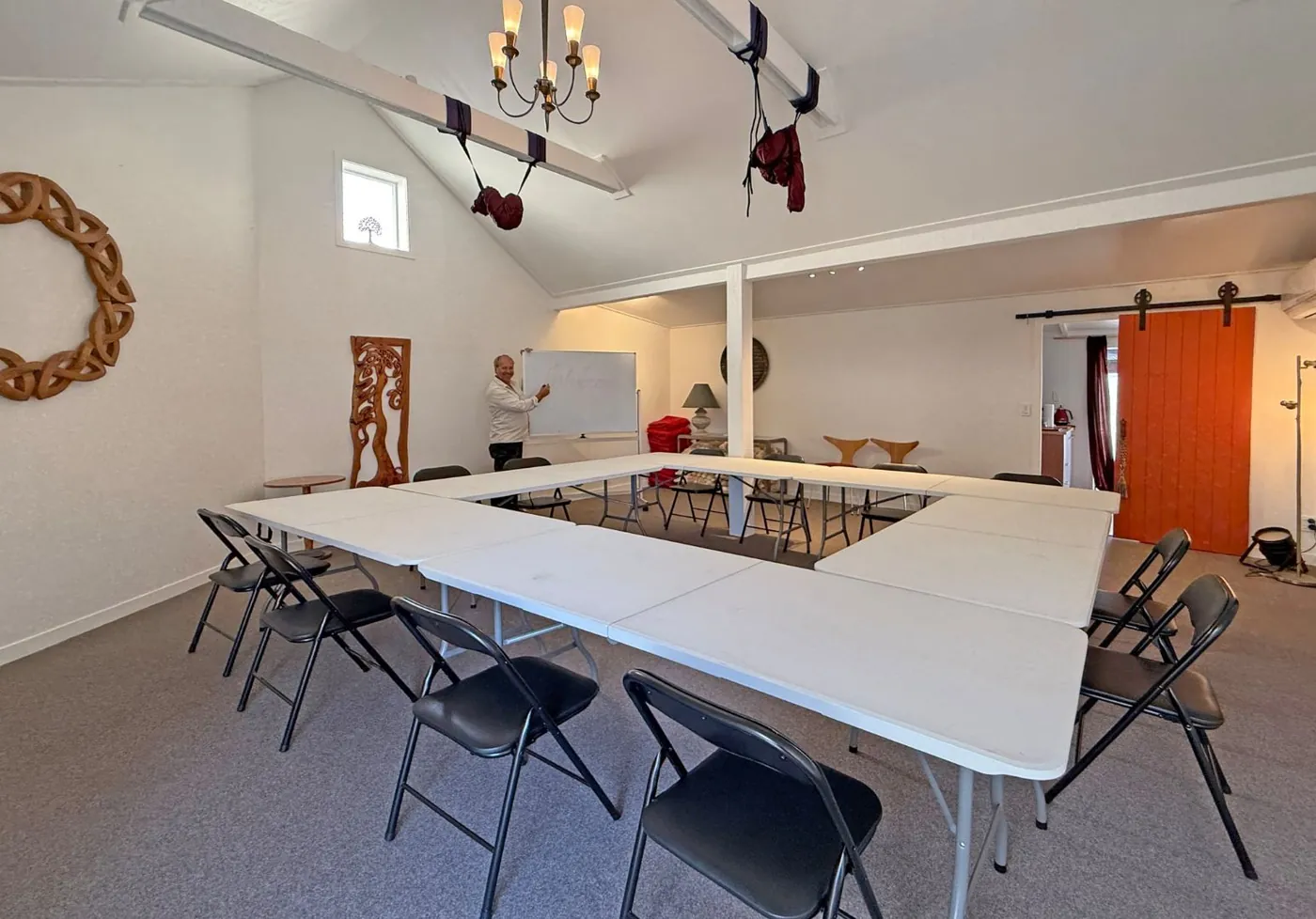 The Embassy of Friendship hall set up with tables and chairs in a square for a workshop, with a facilitator at the whiteboard